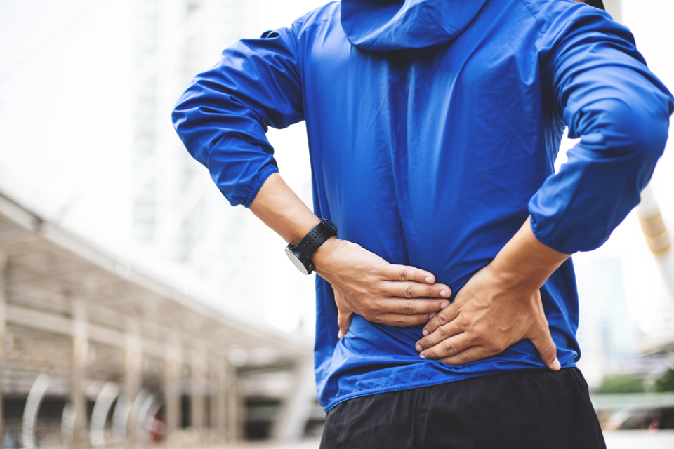 Man taking a break from exercising because he is dealing with back pain caused by chronic inflammation.